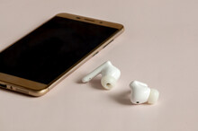 Smartphone and wireless headphones isolated on a light-colored background