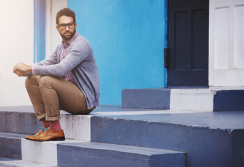 Poster - Man, building and sitting on stairs for fashion, clothes and trendy with glasses outdoor in Cape Town, South Africa. Male person, gen z guy and vision for unique outfit, edgy and urban style