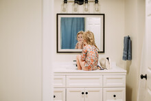 Young Girl Sitting On Bathroom Counter Putting On Mom's Makeup