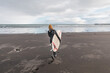 © Cavan Images - Woman walking on beach with surf board winter iceland