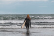 © Cavan Images - Woman walking on beach with surf board winter iceland