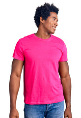 Sticker - Handsome african american man with afro hair wearing casual pink tshirt looking away to side with smile on face, natural expression. laughing confident.