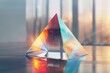 A vibrant and colorful glass pyramid, standing tall against a soft pastel background. The reflections on the surface of each face create an intricate play of light and shadow