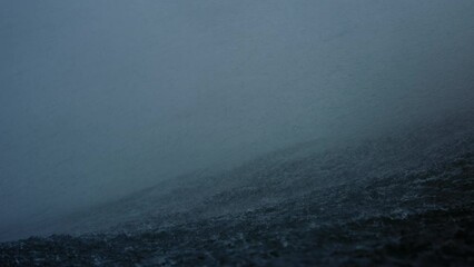 ocean water spray and mist blows over top of wave on stormy day, slow motion in water