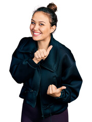 Wall Mural - Young hispanic girl wearing sportswear pointing to the back behind with hand and thumbs up, smiling confident