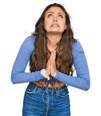 Poster - Young hispanic girl wearing casual clothes begging and praying with hands together with hope expression on face very emotional and worried. begging.