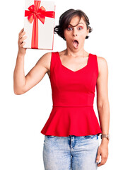 Wall Mural - Beautiful young woman with short hair holding gift thinking attitude and sober expression looking self confident