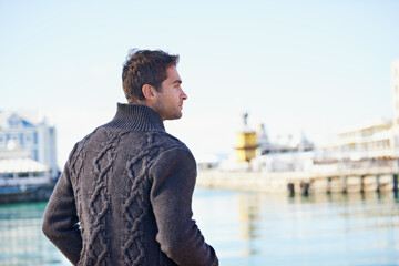 Poster - Man, standing and think with ocean for idea and trip for travel or relax in urban or outdoor for fresh air. Young person and looking for view and harbor for break, wondering and pensive on vacation