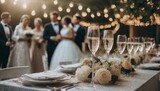 Fototapeta  - Przyjęcie weselne. Stół z zastawą stołową i kieliszkami szampana, w tle goście weselni
