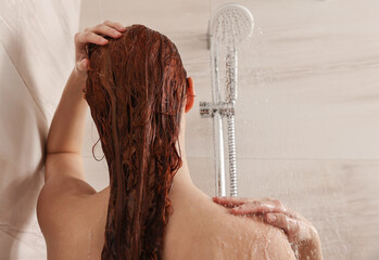 Canvas Print - Young woman washing her hair with shampoo in shower, back view