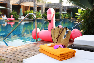 Sticker - Wicker bag with beach accessories on sunbed near outdoor swimming pool, space for text. Luxury resort