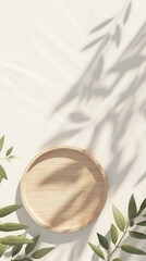 Wall Mural - A wooden plate with olive branch leaves on a white table creates a minimalist composition with a subtle shadow