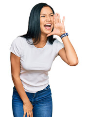 Wall Mural - Beautiful hispanic woman wearing casual white tshirt shouting and screaming loud to side with hand on mouth. communication concept.