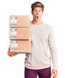 © Krakenimages.com - Young handsome man holding delivery package scared and amazed with open mouth for surprise, disbelief face