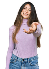 Sticker - Young beautiful teen girl wearing turtleneck sweater smiling cheerful offering palm hand giving assistance and acceptance.