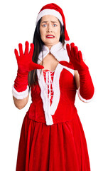 Sticker - Young beautiful caucasian woman wearing santa claus costume afraid and terrified with fear expression stop gesture with hands, shouting in shock. panic concept.