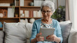 © john - Happy pretty elder woman using digital tablet computer at home, reading electronic book, talking on video call, enjoying online communication, domestic Internet technology