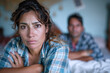 Hispanic woman sad in bedroom, her husband is leaning on the bed