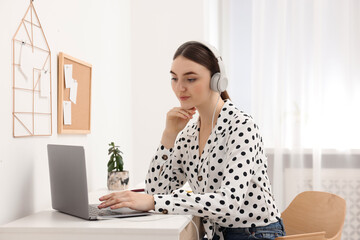 Wall Mural - E-learning. Young woman using laptop during online lesson at table indoors