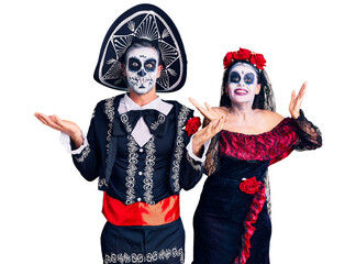 Wall Mural - Young couple wearing mexican day of the dead costume over background celebrating crazy and amazed for success with arms raised and open eyes screaming excited. winner concept