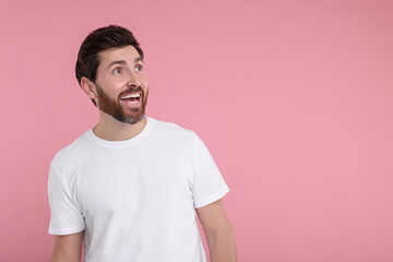 Poster - Portrait of happy surprised man on pink background, space for text