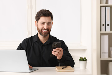 Poster - Smiling man using smartphone at table in office