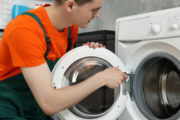 Sticker - Young plumber repairing washing machine in bathroom