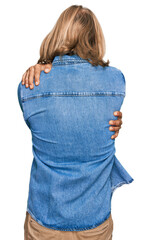 Canvas Print - Caucasian man with blond long hair wearing casual denim jacket hugging oneself happy and positive from backwards. self love and self care