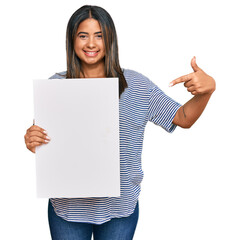 Sticker - Young latin girl holding blank empty banner smiling happy pointing with hand and finger