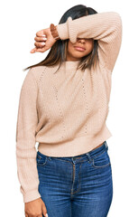 Wall Mural - Young latin girl wearing wool winter sweater covering eyes with arm, looking serious and sad. sightless, hiding and rejection concept