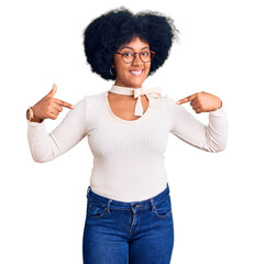 Sticker - Young african american girl wearing casual clothes and glasses looking confident with smile on face, pointing oneself with fingers proud and happy.