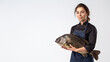 A pleasant female chef is handling a large freshwater fish with care on a plain background