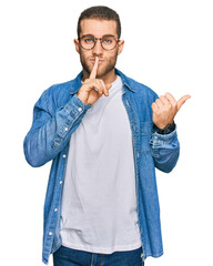 Poster - Young caucasian man wearing casual clothes asking to be quiet with finger on lips pointing with hand to the side. silence and secret concept.