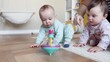 baby group playing spinning top toy. kindergarten a happy childhood concept. baby twins with mom play toy whirligig indoors. baby group in kindergarten with a teacher play top in lifestyle playroom