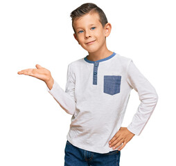 Wall Mural - Adorable caucasian kid wearing casual clothes smiling cheerful presenting and pointing with palm of hand looking at the camera.