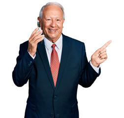 Poster - Senior business man with grey hair having conversation talking on the smartphone smiling happy pointing with hand and finger to the side