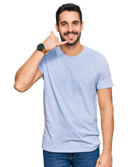 Wall Mural - Young hispanic man wearing casual clothes smiling doing phone gesture with hand and fingers like talking on the telephone. communicating concepts.