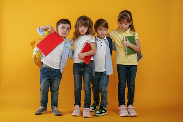  Notepads in hands, conception of education. Kids are together against yellow background