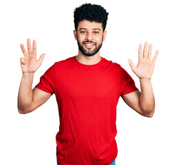 Canvas Print - Young arab man with beard wearing casual red t shirt showing and pointing up with fingers number nine while smiling confident and happy.