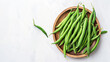 Green beans in a wooden plate on a white background, top view