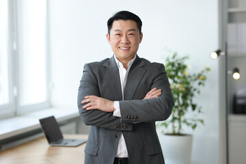 Wall Mural - Portrait of smiling businessman with crossed arms in office