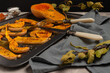 Baked pumpkin slices with spices and bay leaves on a dark baking sheet. Selective focus.