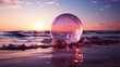 A glass ball lies in the waves on the sandy beach, the sea and the setting sun are reflected in the ball.
