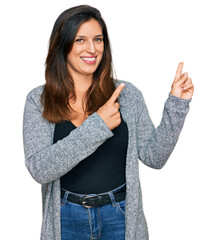 Wall Mural - Beautiful hispanic woman wearing casual clothes smiling and looking at the camera pointing with two hands and fingers to the side.