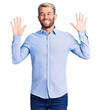 © Krakenimages.com - Young handsome blond man wearing elegant shirt showing and pointing up with fingers number ten while smiling confident and happy.