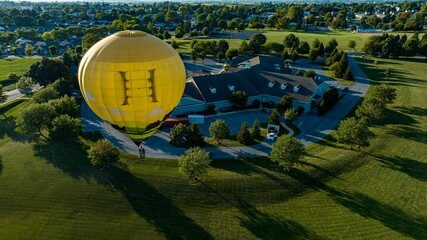 Aerial View on a Yellow Hot Air Balloon Floating Over a Countryside Community