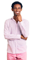 Wall Mural - African handsome man wearing casual pink shirt looking confident at the camera with smile with crossed arms and hand raised on chin. thinking positive.