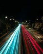 © Wirestock - Car driving along a road at night in a long exposure image, creating a light trail
