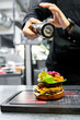 Professional chef finalizing a gourmet burger in a kitchen, demonstrating culinary expertise and creativity