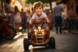 A little boy in a t shirt and shorts rides a golden toy quad bike on an evening street with blurred people in the background